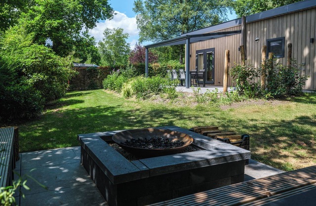 Enjoy a luxurious holiday home for 4 people in the wooded nature of the Veluwe, complete with modern amenities, air conditioning, a stylish pergola, and a cozy lounge area with an outdoor fireplace for ultimate comfort and ambiance, both day and nigh