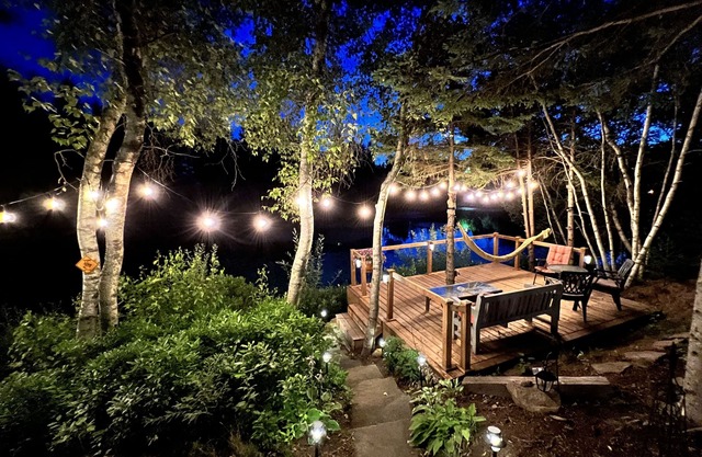 Luxurious rustic wooden chalet on edge of tranquil pond in nature next to beach.