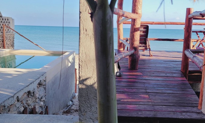 Chuburna Puerto Cottage | Pasilla suite. Ocean view glass doors to the turquoise water, 13foot Tv screen