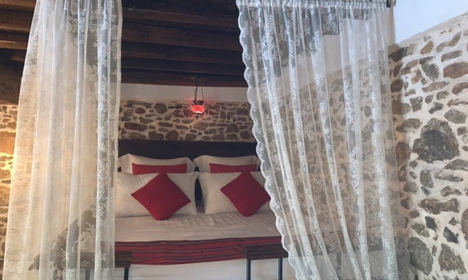 Asklipiio House | Traditional stone built single room house with traditional bed.